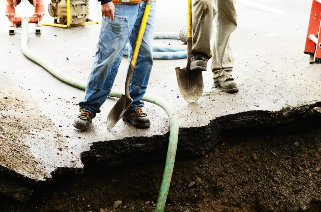 two workers by sinkhole with shovels