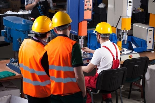 Industrial Hygiene Three laborers in safety helmets are working in factory