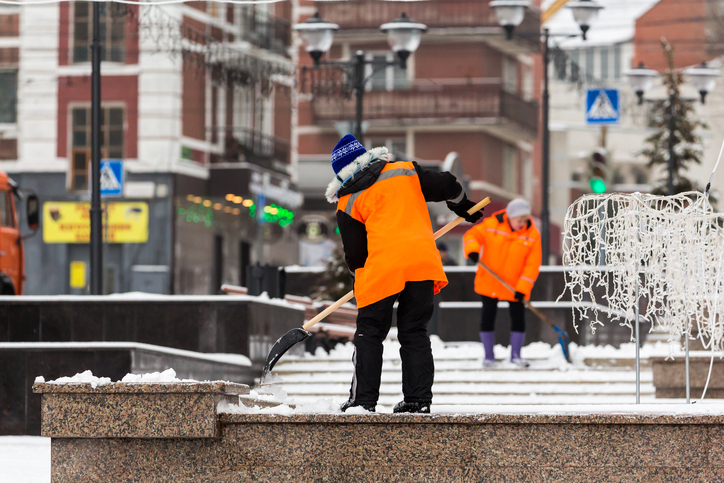 workers shoveling snow in winter in city